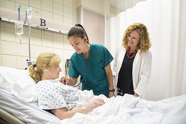 Nursing student with instructor and patient