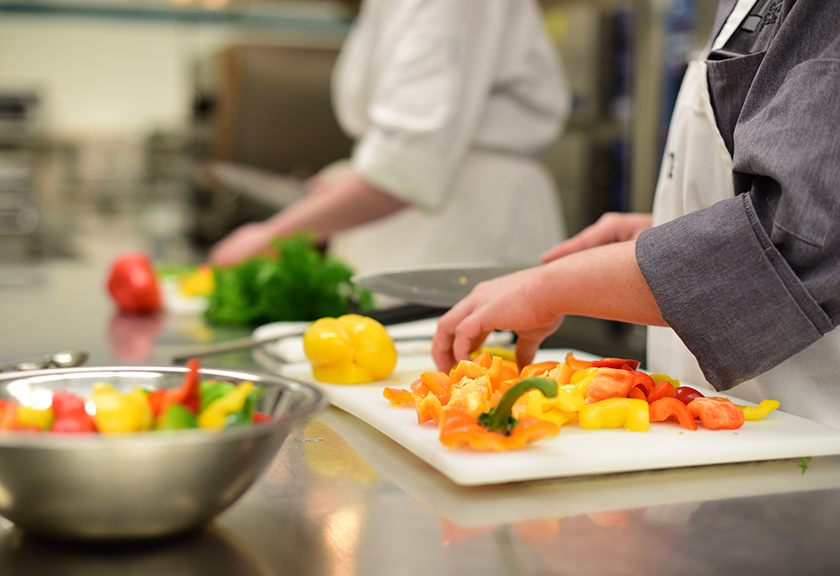 Culinary students chopping vegetables in kitchen