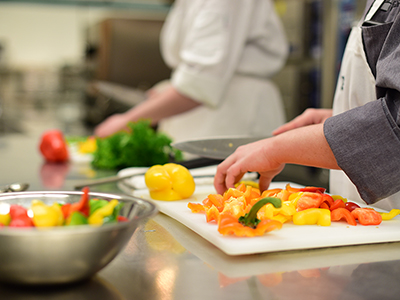Culinary students chopping vegetables in kitchen