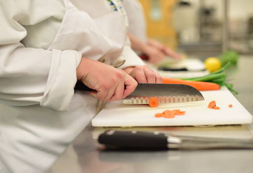 Culinary student chopping carrots