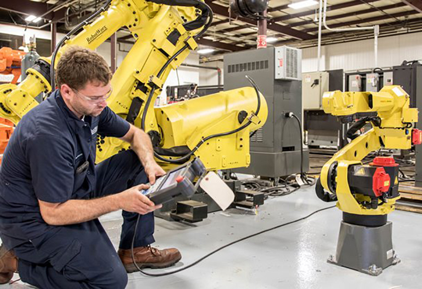 Worker checking robotics used in manufacturing